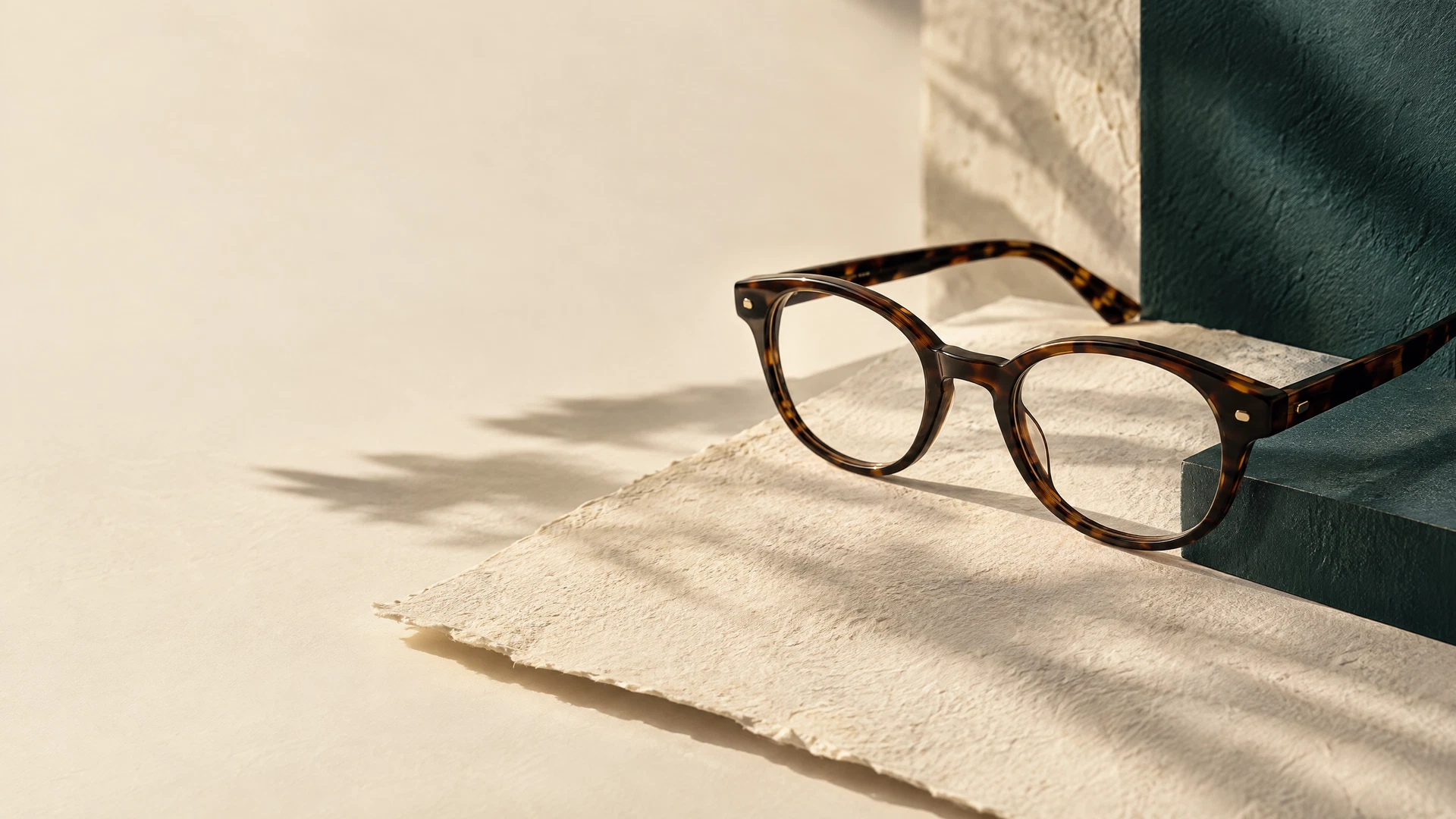 Illustrative editorial still life of eyeglasses on warm paper and a deep teal surface